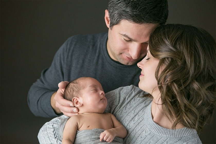 mom and dad together holding newborn