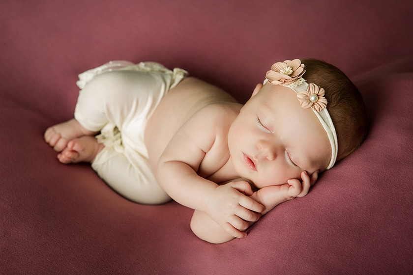 sleeping newborn on maroon blanket