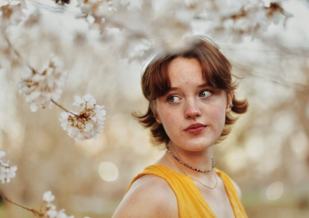 senior girl standing in front of a tree with white flowers