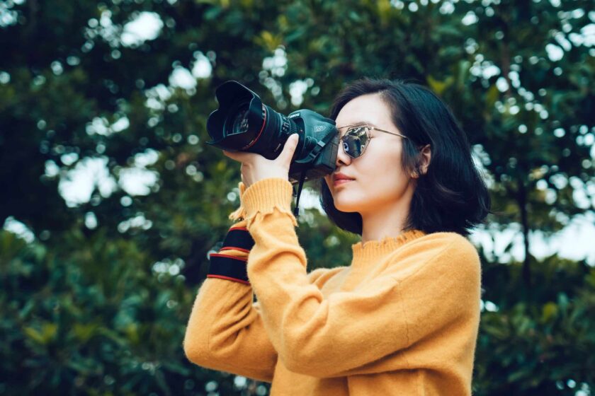 woman taking photo near tree