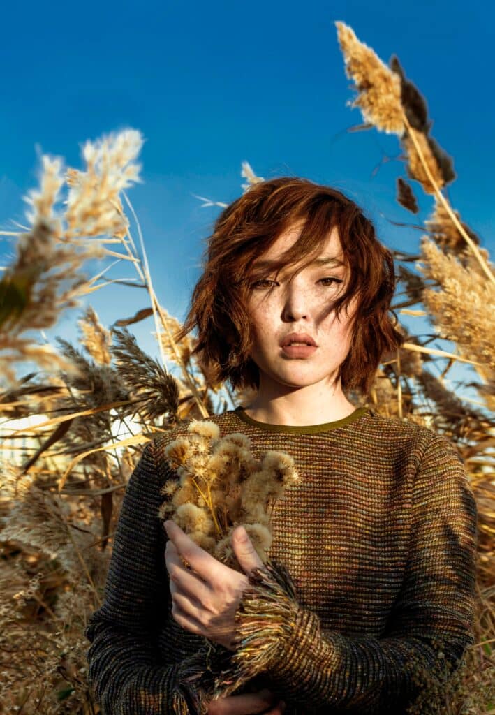 asian woman standing in a field of tall grasses