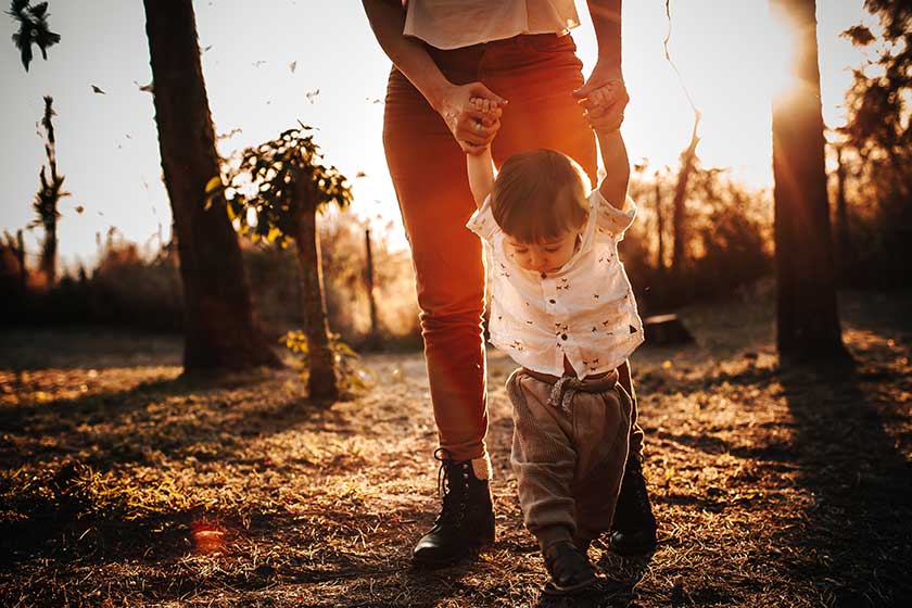 baby holding mother's hands taking steps