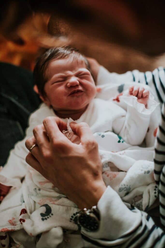 baby scrunching their face while being held in a persons lap