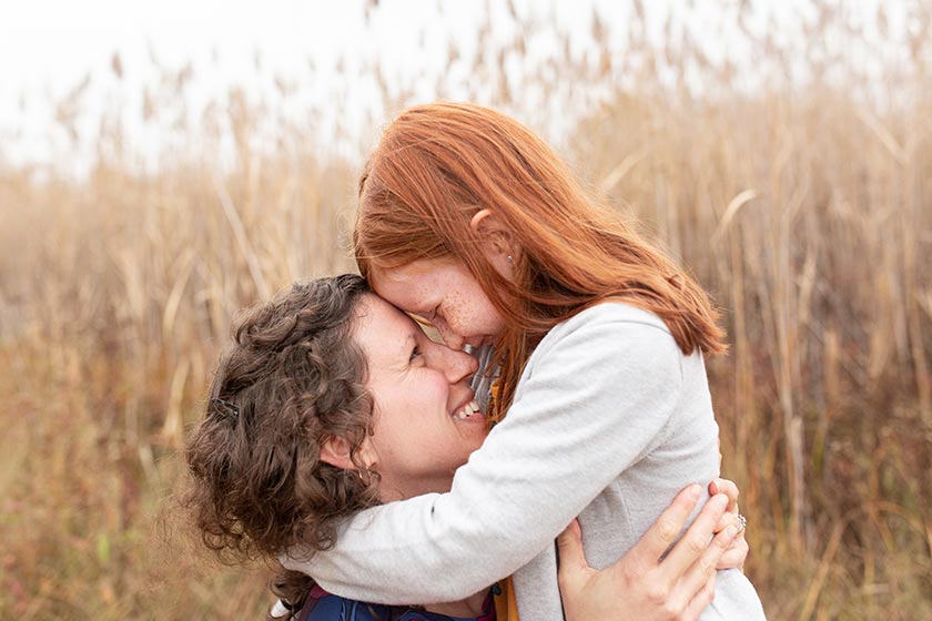 Photo of mother and daughter hugging and touching foreheads with beautiful natural light