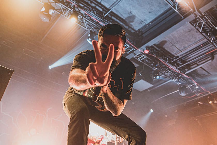 performer giving peace sign on stage at concert