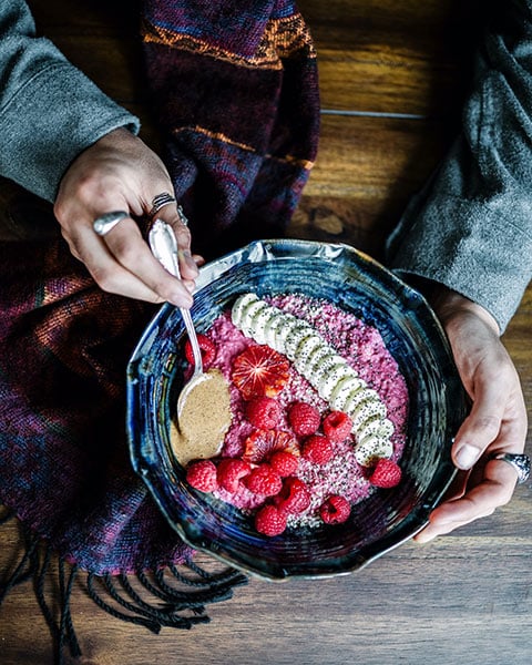 person eating a bowl of fruit and grains