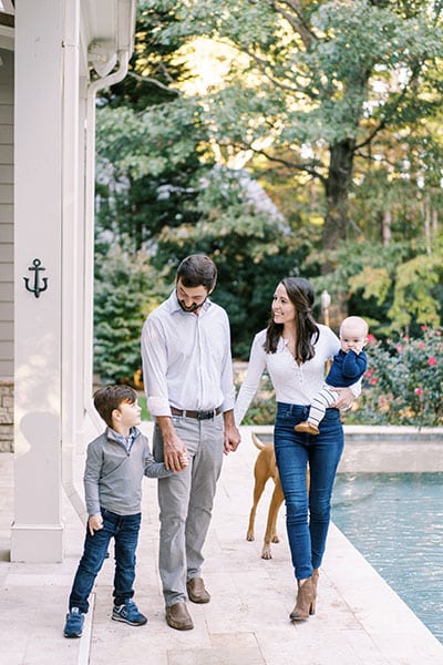 family and dog posing beside pool