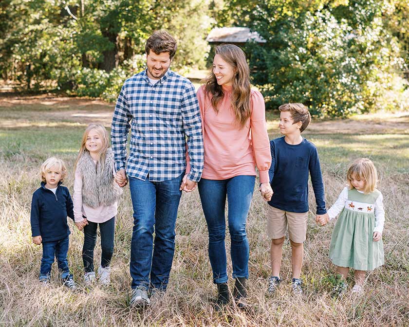 mom and dad holding hands with four children