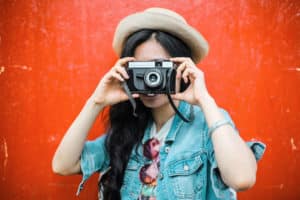 woman taking photograph in front of red-orange background