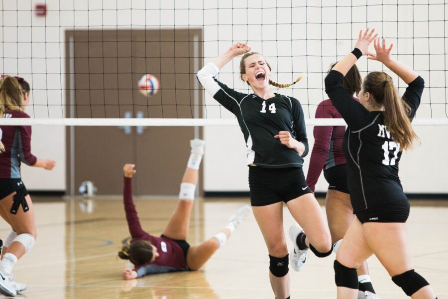 female volleyball teammates about to high five after scoring