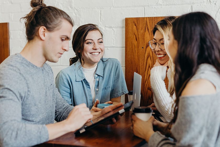 four people sitting around a table networking