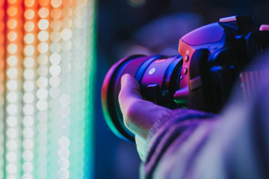 hand holding camera toward bokeh multicolor lights