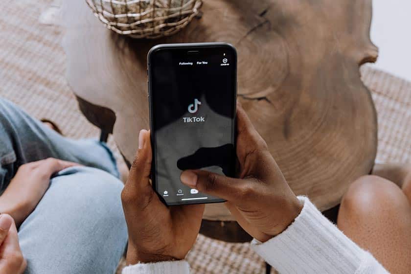 hands holding a mobile phone with the TikTok logo displayed on the screen