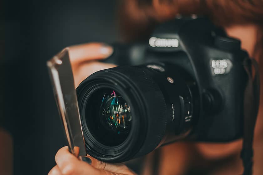 person taking photo holding reflective material near camera lens