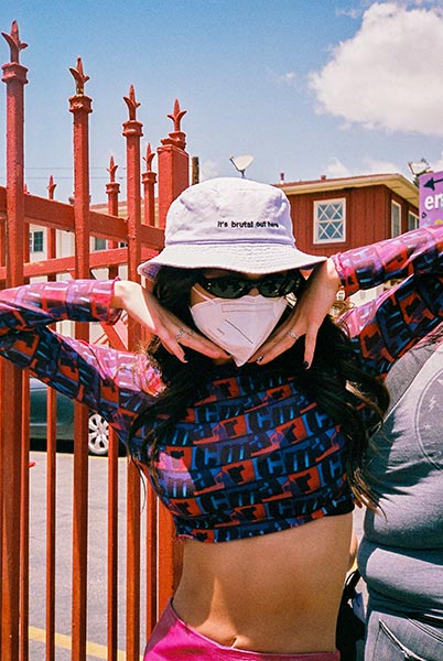 woman posing in crop top and hat that reads: "It's brutal out here"