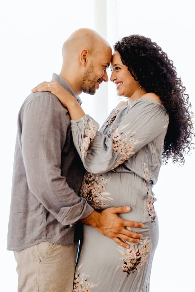 man in grey shirt facing woman in grey floral dress, their foreheads touching