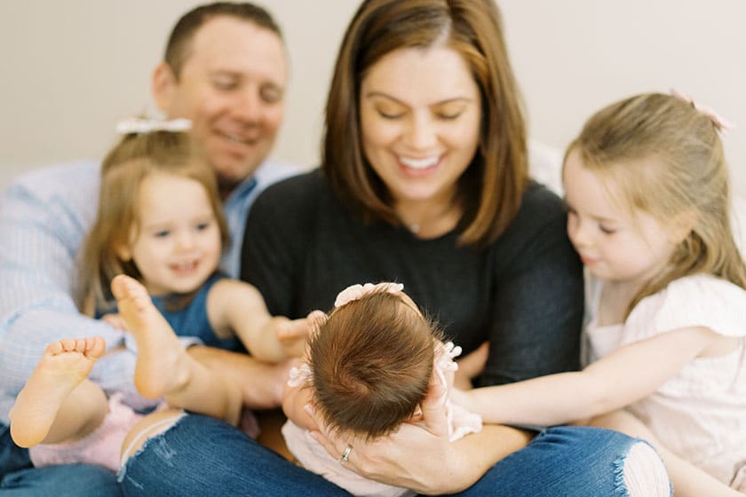 newborn baby with sisters and parents