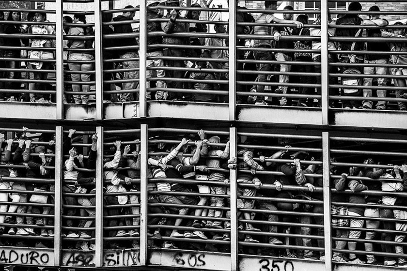 people piled tightly in lines, up against tall fences