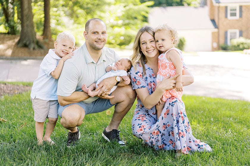 family of five cuddled close in the grass outdoors