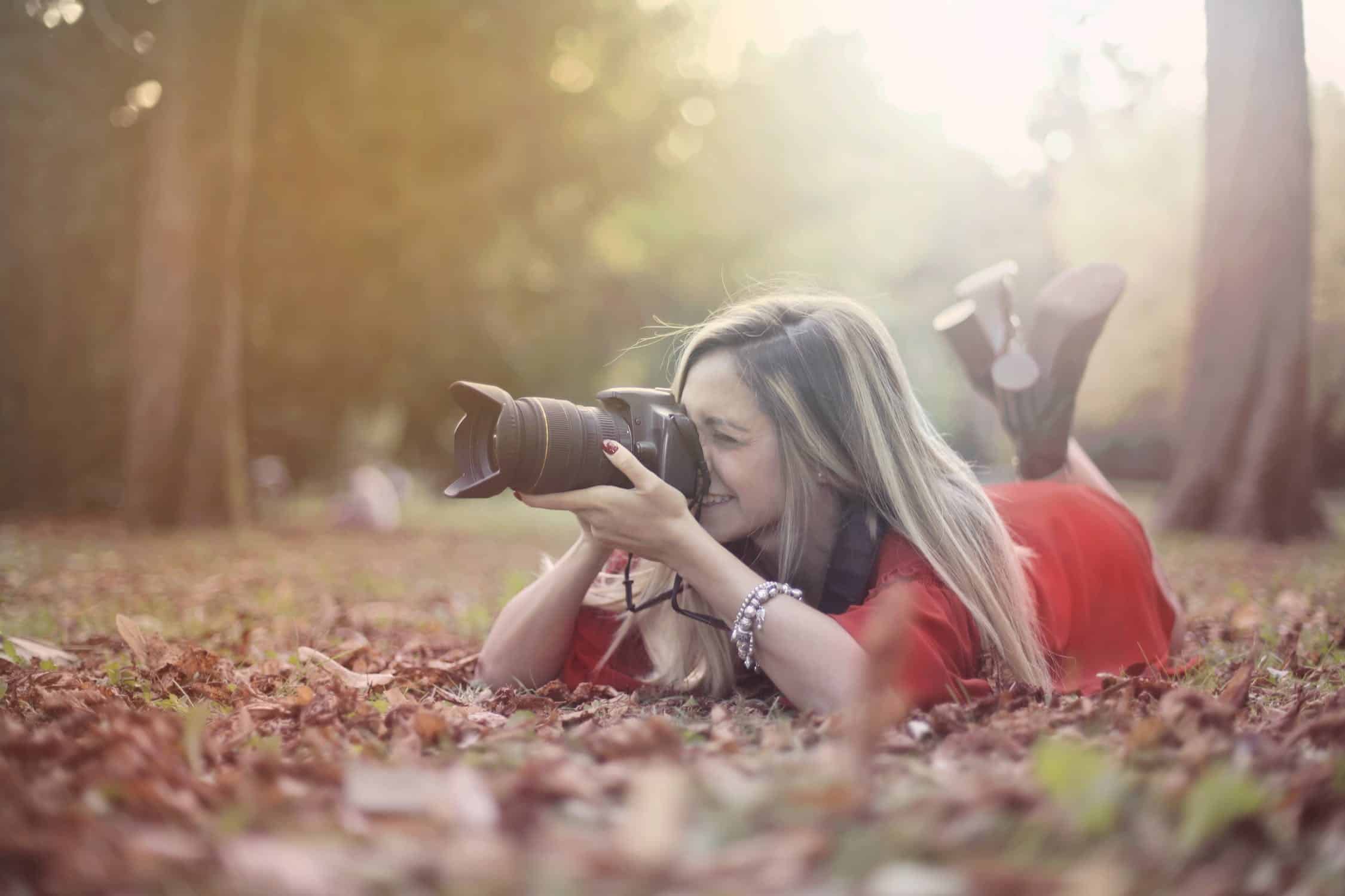 photographer shooting prone in a forest field on leaves