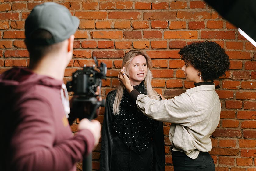 hair and makeup artist fixing hair of woman in photo session