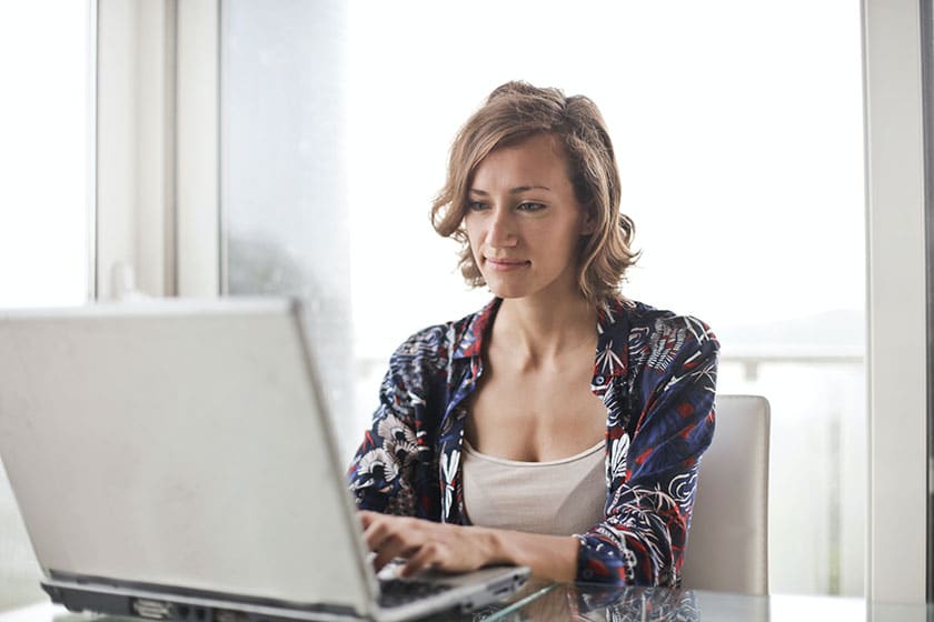 woman sitting at table using laptop