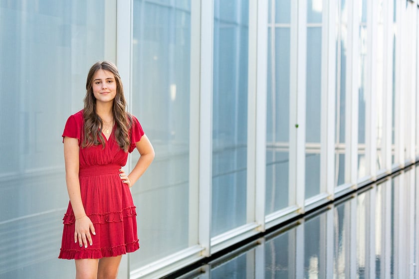 Teen girl in red dress beside row of windows