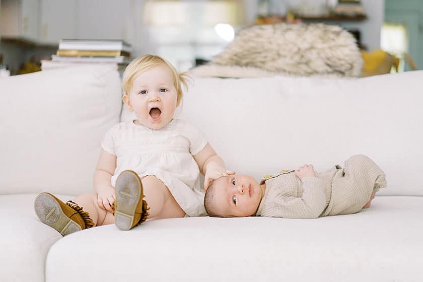 toddler and newborn sibling on couch