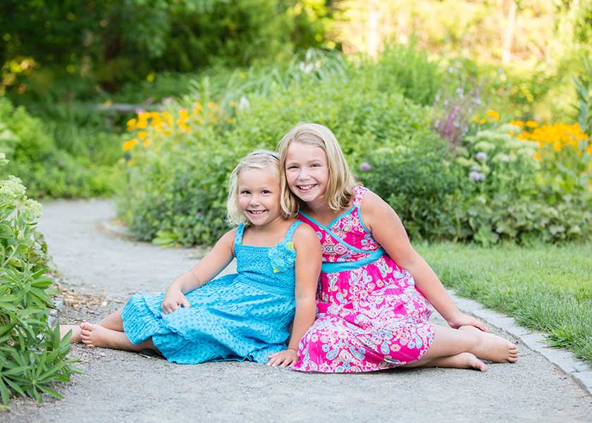 two girls sitting in garden path