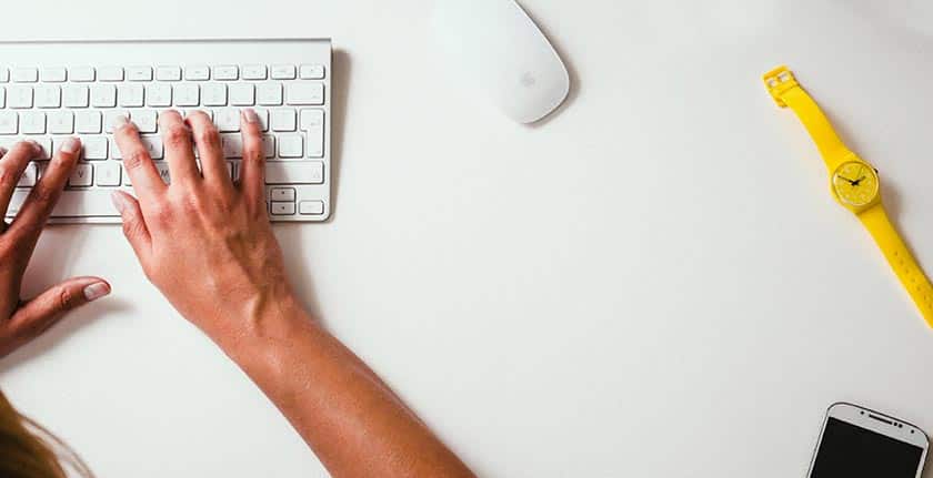 hands typing on keyboard with watch and mouse nearby