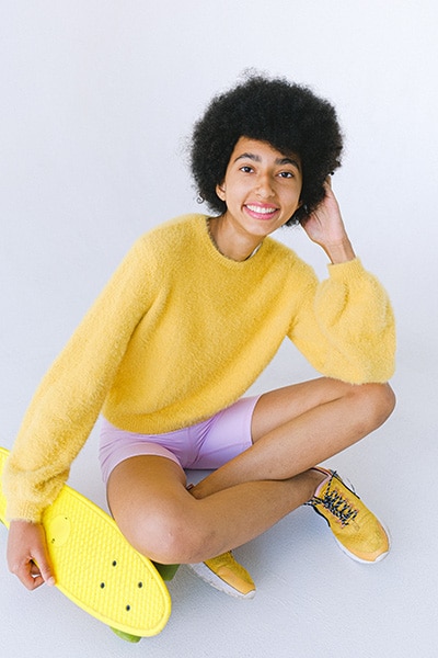 teenage girl posing cross-legged with one elbow resting on her knee