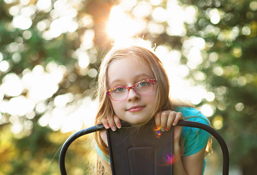 Girl wearing glasses and leaning on chair