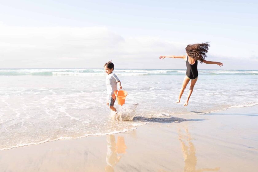 two children playing by the ocean waves