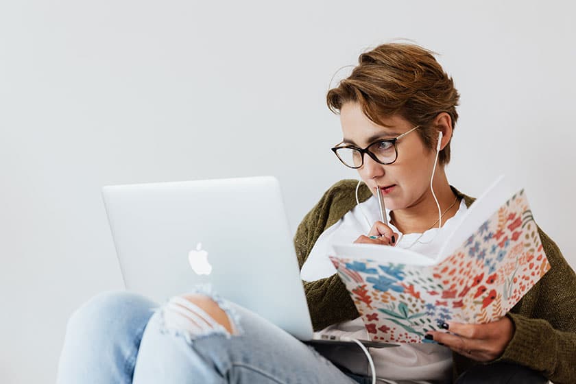 woman holding notebook and concentrating on laptop