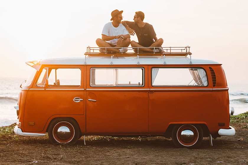 two guys sitting atop a retro camper bus