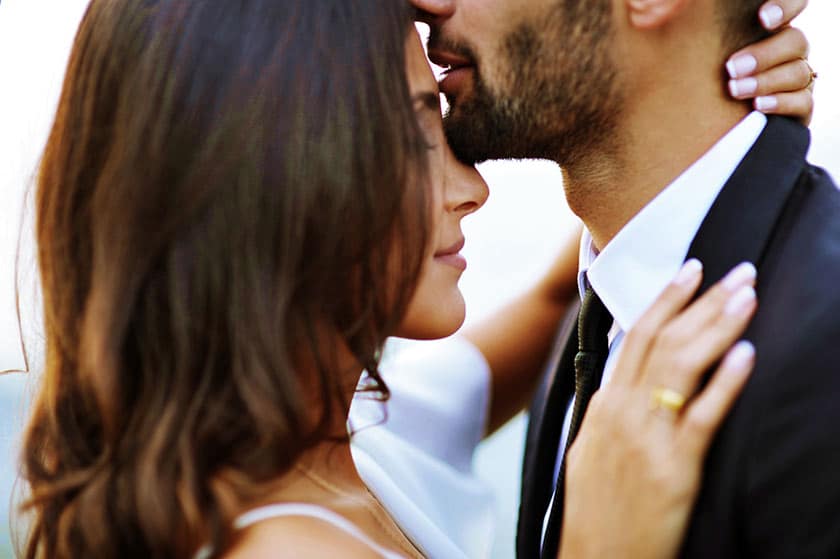 Groom kissing bride on forehead