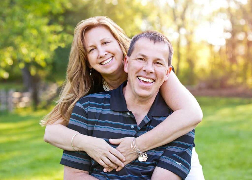 woman hugging man from behind both facing camera