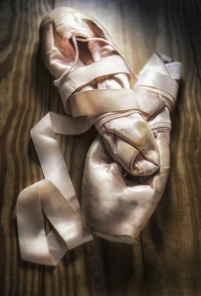 worn ballet pointe slippers on a wooden surface